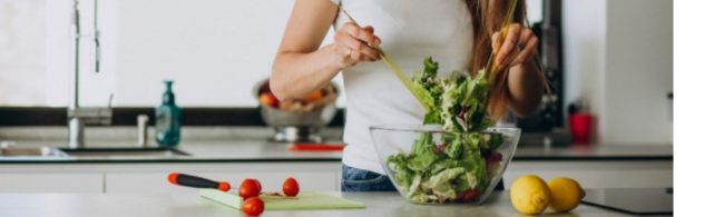 Frau bereitet einen gesunden Salat für Fitnessernährung zu.