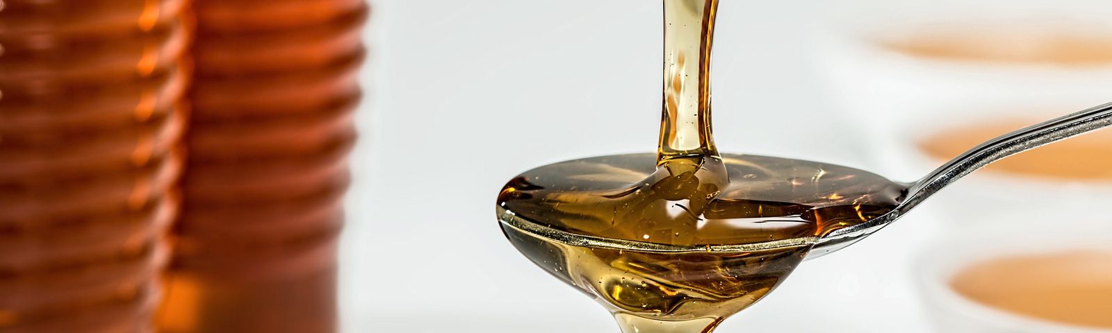 Sirup auf einem Löffel, vor einem unscharfen Hintergrund, der eine Ernährung für Fitnesskunden symbolisiert.