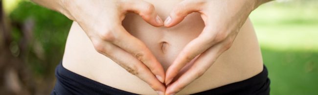 Hände bilden ein Herz über dem Bauch. Fitnesstipps und gesunde Ernährung für ein Herz-Kreislauf-System.