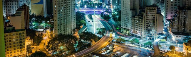 Dynamische nächtliche Stadtszene mit leuchtenden Autos und hohen Gebäuden, die Bewegung und Energie widerspiegeln, inspirierend für Fitness und Ernährung.