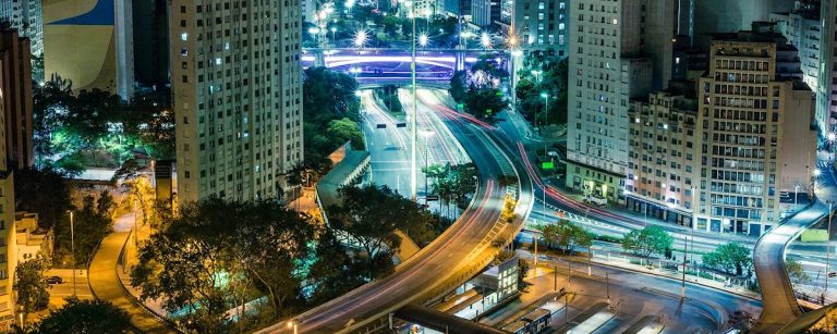 Dynamische nächtliche Stadtszene mit leuchtenden Autos und hohen Gebäuden, die Bewegung und Energie widerspiegeln, inspirierend für Fitness und Ernährung.