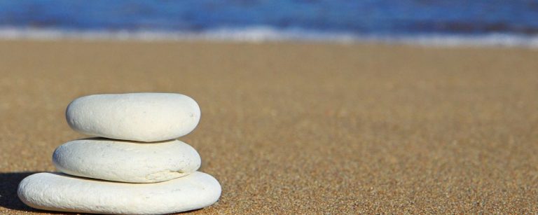 Balance: Gestapelte Steine am Strand, die Ruhe und Konzentration für Ihr Fitness-Training symbolisieren.