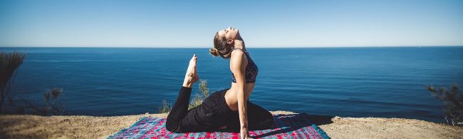 Junge Frau praktiziert Yoga am Meer für Fitness und Wohlbefinden.