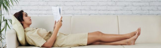 Frau entspannt auf Sofa und liest Buch, gesunde Ernährung und Fitness.