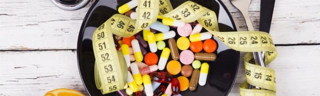 Gesunde Ernährung und Gewichtsverlust mit Medikamenten und Messband auf schwarzem Teller.