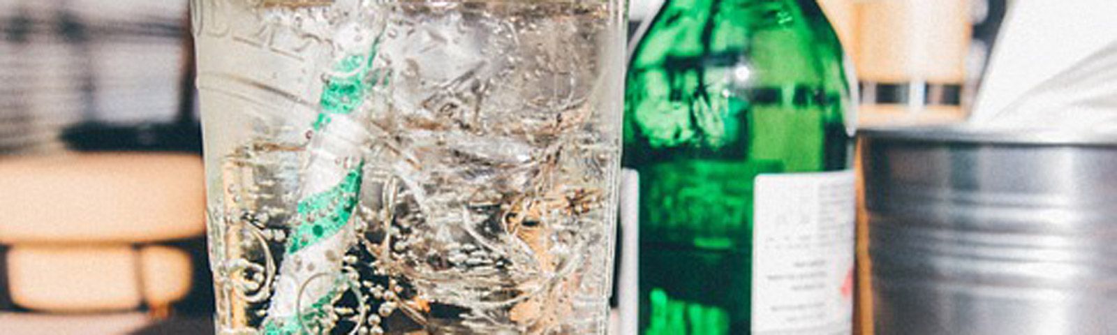 frisdrank-g Kühles, sprudelndes Getränk mit Eis und Strohhalm neben einer grünen Flasche – perfekt für Fitness und Ernährung.