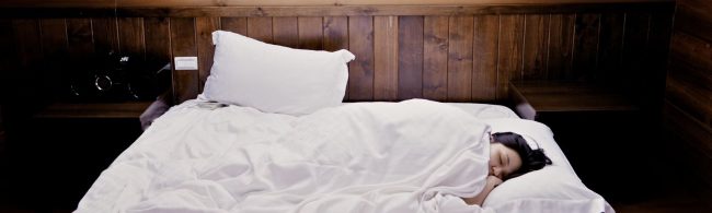 Eine Frau schläft im Bett, was auf eine gesunde Erholung für Fitness und Ernährung hinweist.