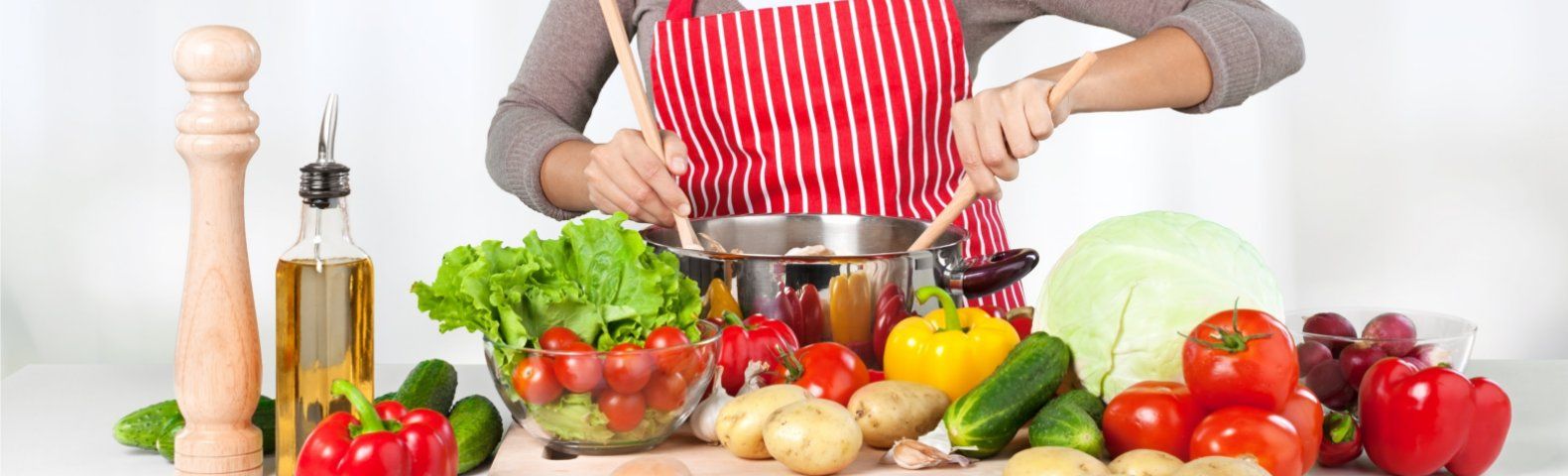 novembergerechtgroot Person kocht gesundes Essen mit frischem Gemüse und Kräutern in einer Küche.