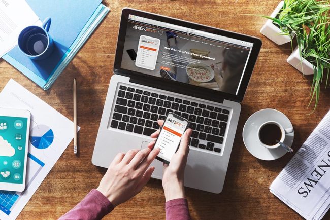 Ein Laptop und Smartphone zeigen die BenFit Lifestyle-App, die ein Ernährungs- und Fitnessprogramm anbietet.