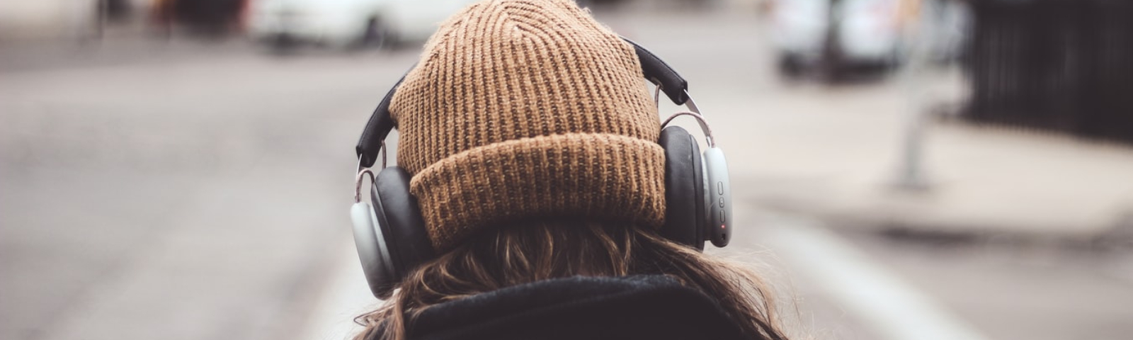 relaxen met muziek 1600×480 Frau mit Kopfhörern und Beanie hört Musik beim Sporttraining.