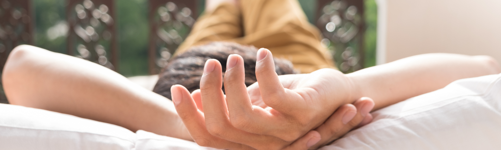 rustdag 1600×480 Entspannter Mensch mit Händen hinter dem Kopf auf weißem Kissen, ein Symbol für Erholung nach dem Training.