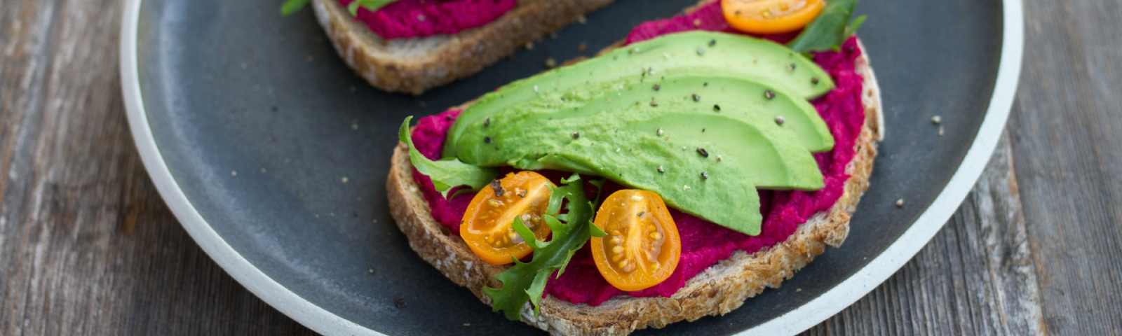 Vegane Avocado-Toast mit Rote-Bete-Aufstrich und Tomaten für gesunde Ernährung.