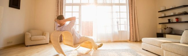 Mann entspannt in einem modernen Wohnzimmer, umgeben von hellem Licht.