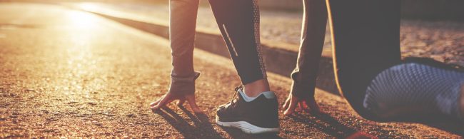 Läuferin in Startposition im Sonnenuntergang für Fitness und Ernährung.