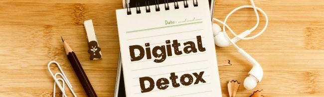 Digitale-detox Schreibtisch-Layout für digitale Entgiftung mit Notizbuch, Stift, Kopfhörern und Büroklammern.