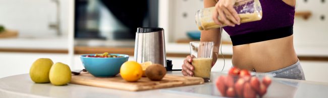 Frau macht Smoothie in der Küche, gesunde Ernährung für Fitness.