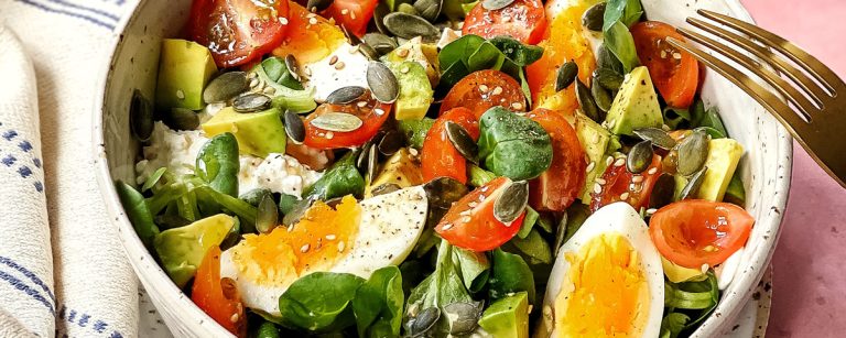 Gesunder Fitness-Salat mit Ei, Avocado, Tomaten und Kernen.