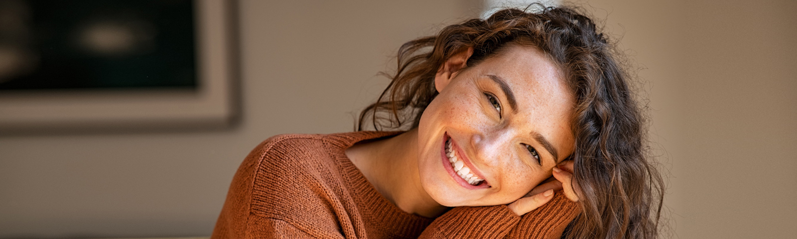 Lächelnde Frau mit Sommersprossen in orangefarbenem Pullover – Fitness und gesunde Ernährung.