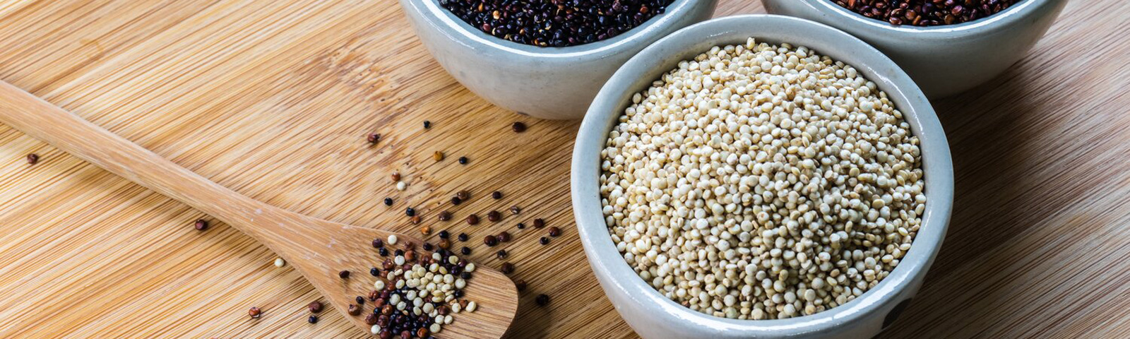 Close-up of cooked white, red and black quinoa in bowls, highlighting the grain-like seeds and their texture.