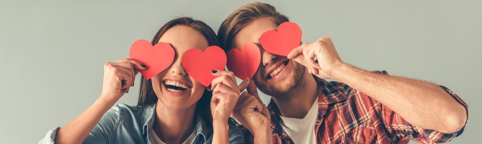 A cozy romantic dinner setup with candles, flowers, elegant napkins and soft lighting.