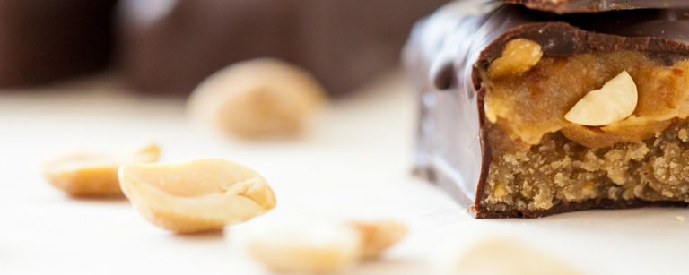 Close-up of homemade healthy Snickers bars with date caramel, peanuts and dark chocolate coating