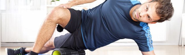 Man performing side-lying foam rolling on the outer thigh to release fascia