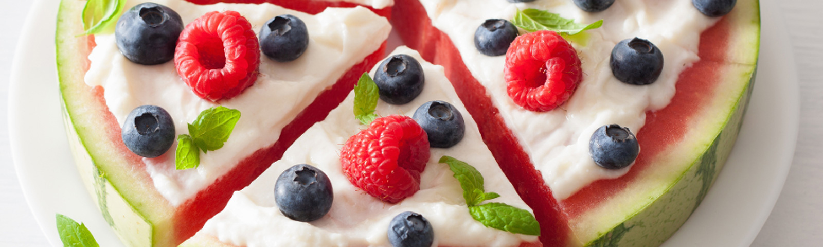 Watermelon slice topped with Greek yogurt, raspberries, blueberries and mint